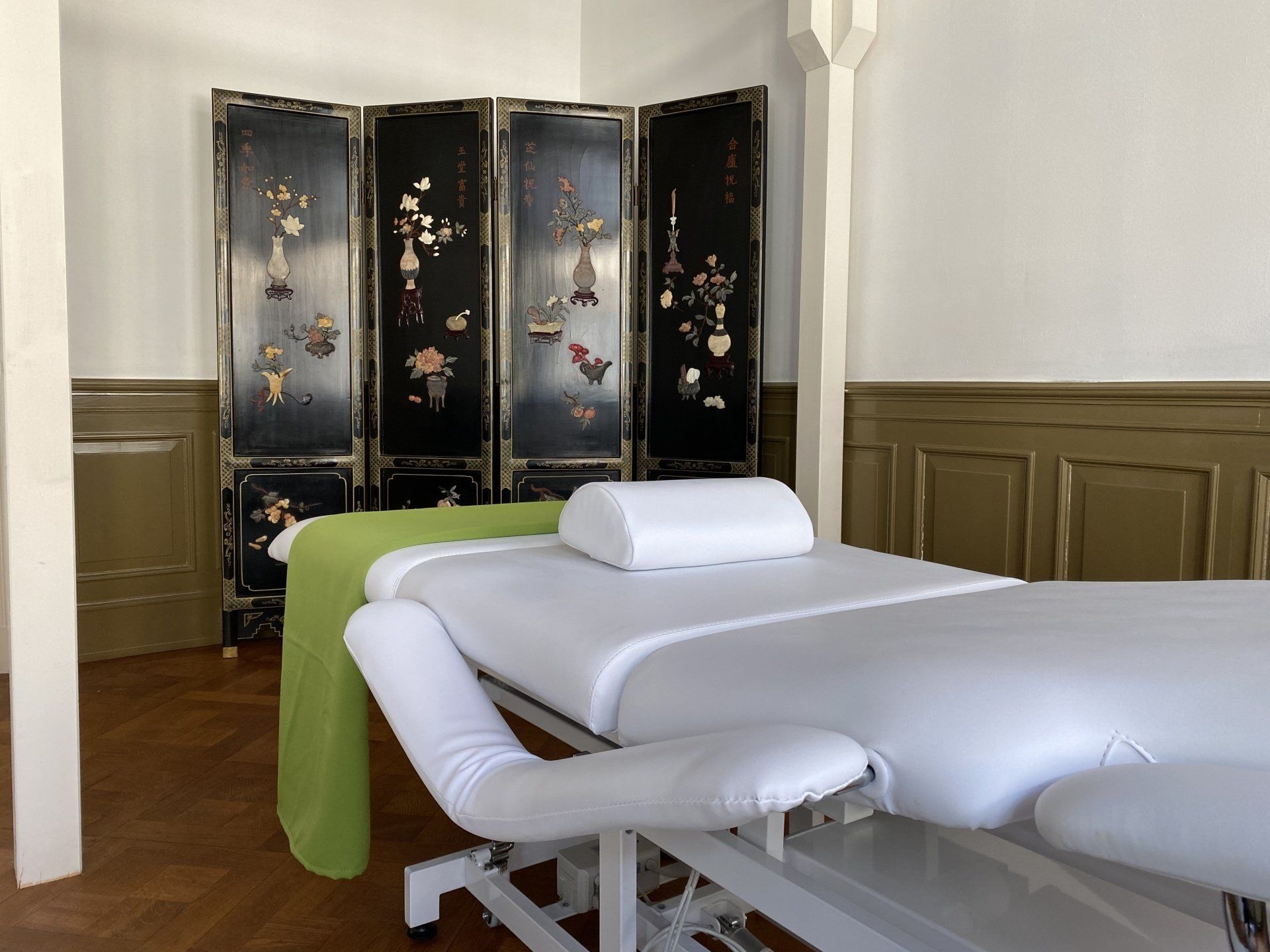 Eine Massageliege in einem Raum mit einem grünen Handtuch darauf