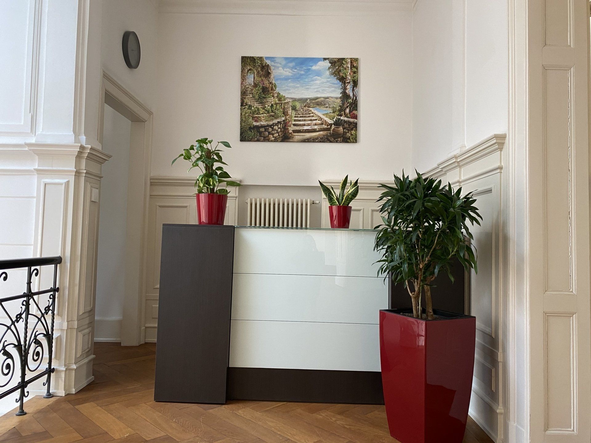 Ein Empfangsbereich mit einem weißen Tresen und zwei Topfpflanzen.