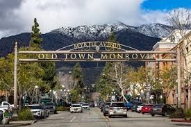 A metal arch over Myrtle Avenue in Old Town Monrovia, with snow-covered mountains in the background.