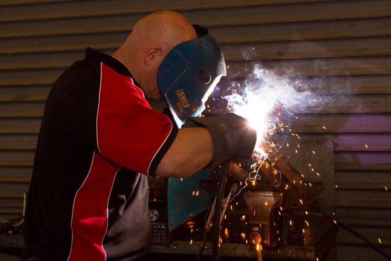 A Man Wearing A Welding Mask Is Welding A Piece Of Metal — CS Mechanical Repairs & Services In Wauchope, NSW