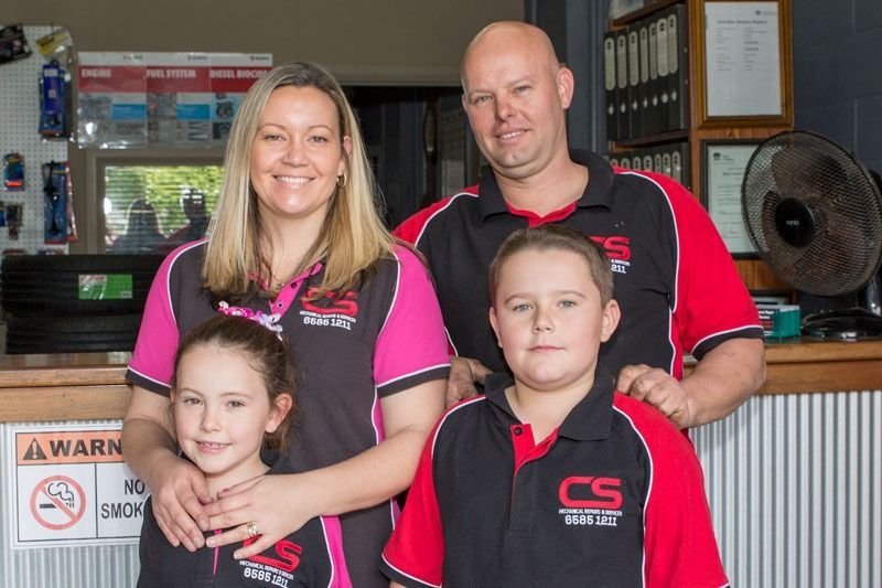 A Family Is Posing For A Picture In Front Of A Counter — CS Mechanical Repairs & Services In Wauchope, NSW