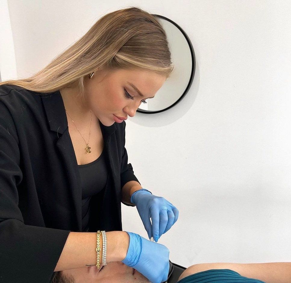 A woman wearing blue gloves is working on a man 's face.