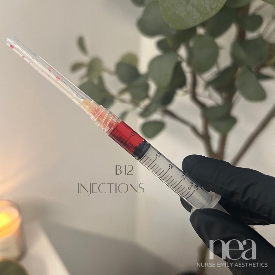 A person is holding a syringe with red liquid in it.