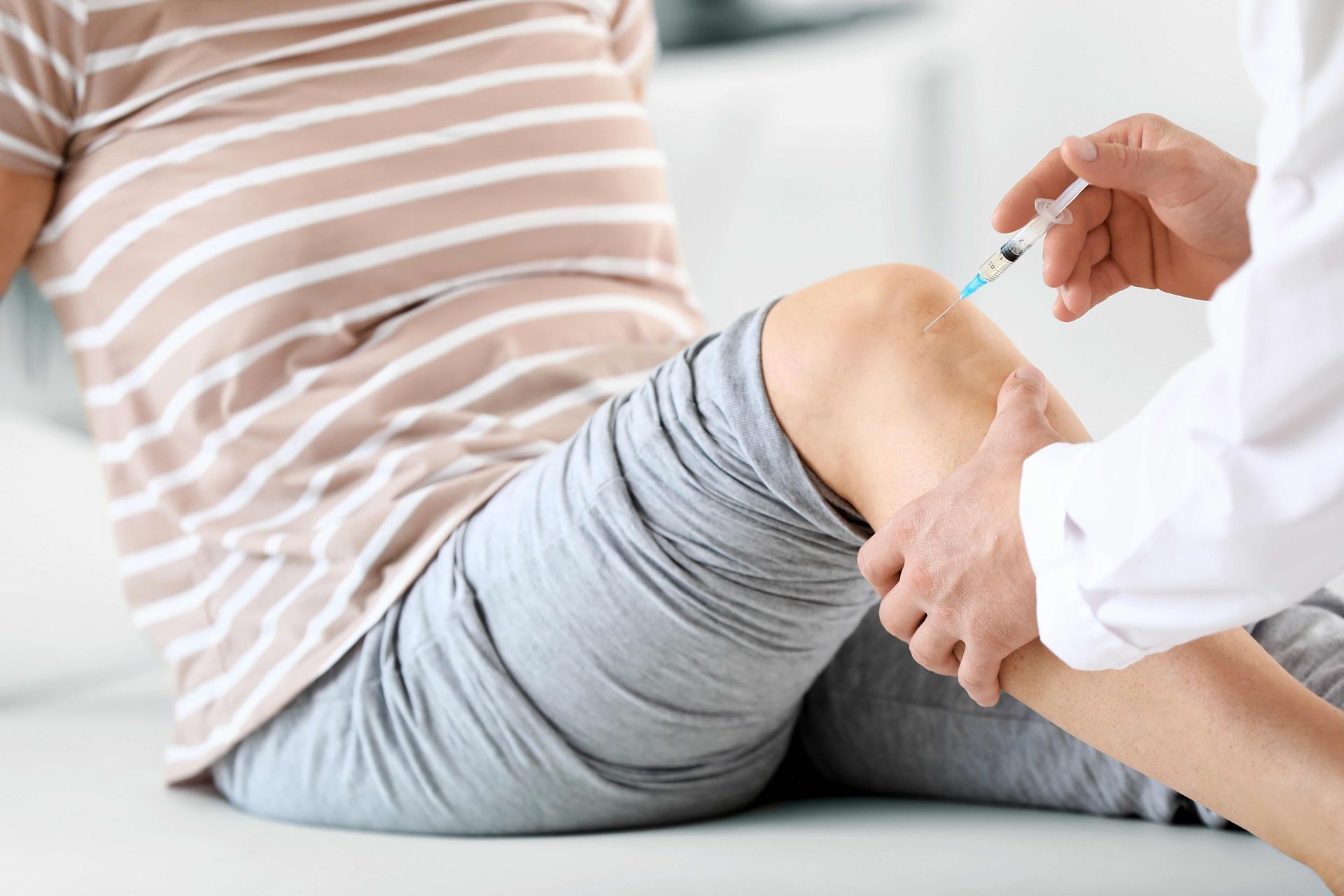 A pregnant woman is getting an injection in her leg.