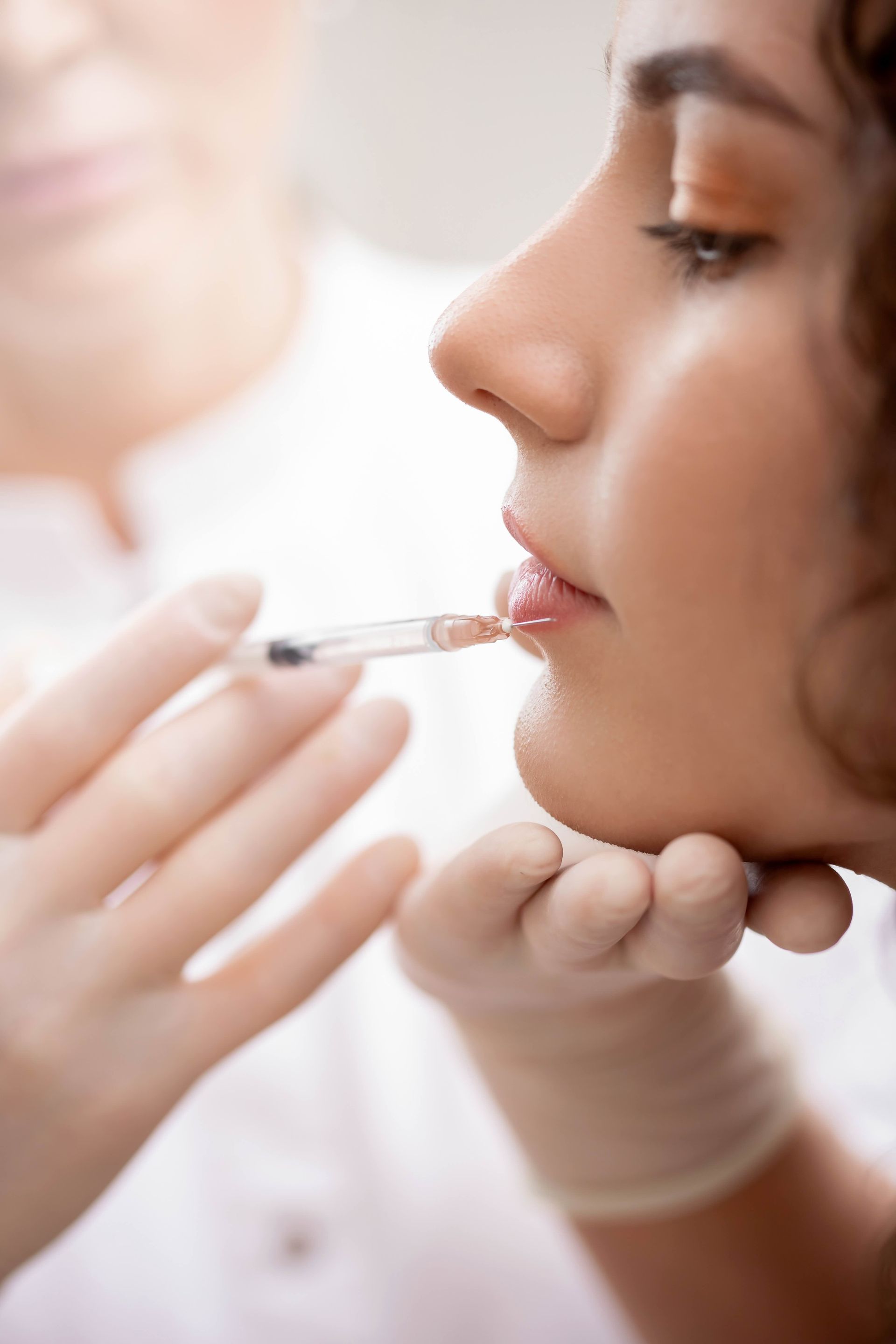 A woman is getting a botox injection in her lips.