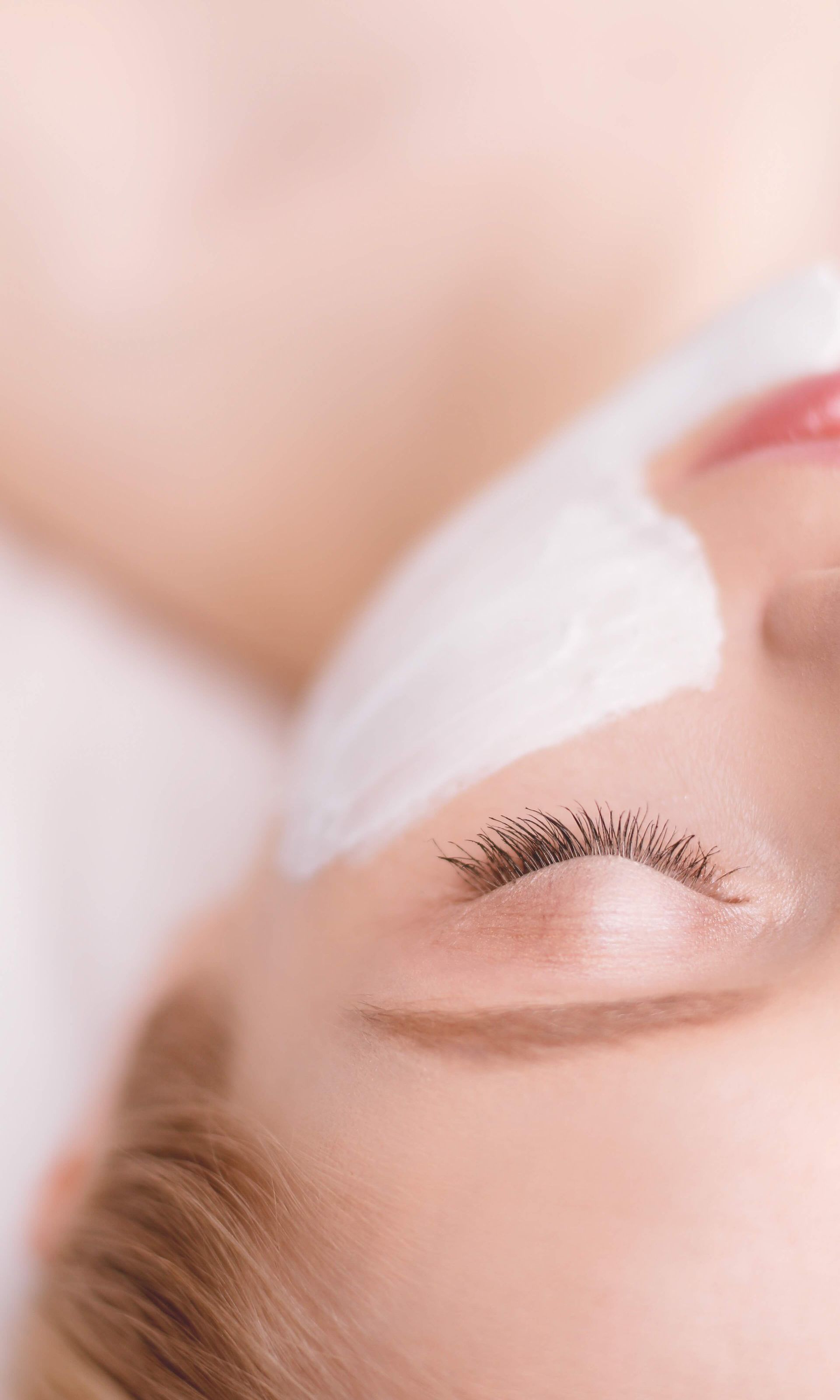 A woman is getting eyelash extensions in a beauty salon.