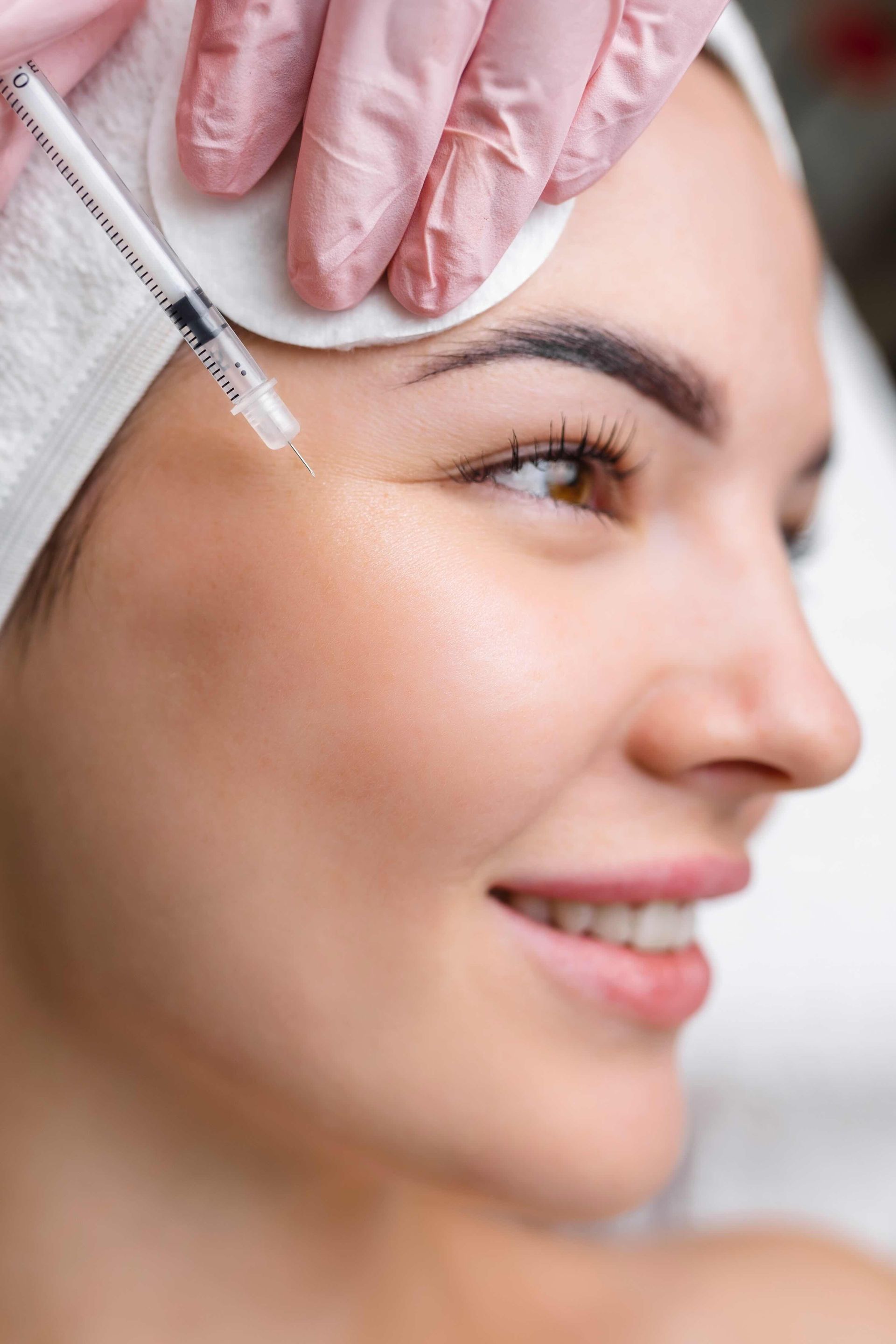 A woman is getting a botox injection in her forehead.