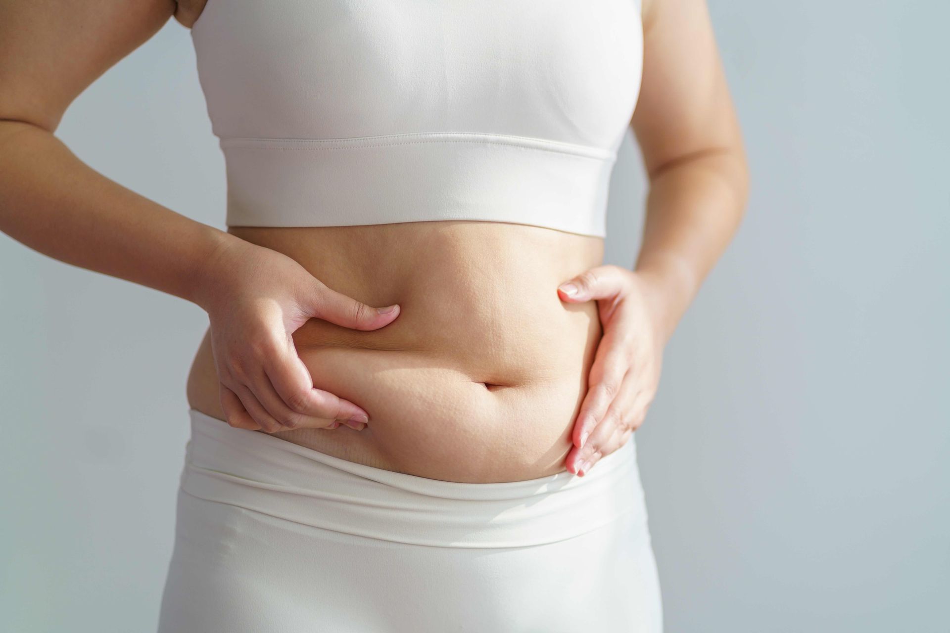 A woman is holding her belly with her hands.