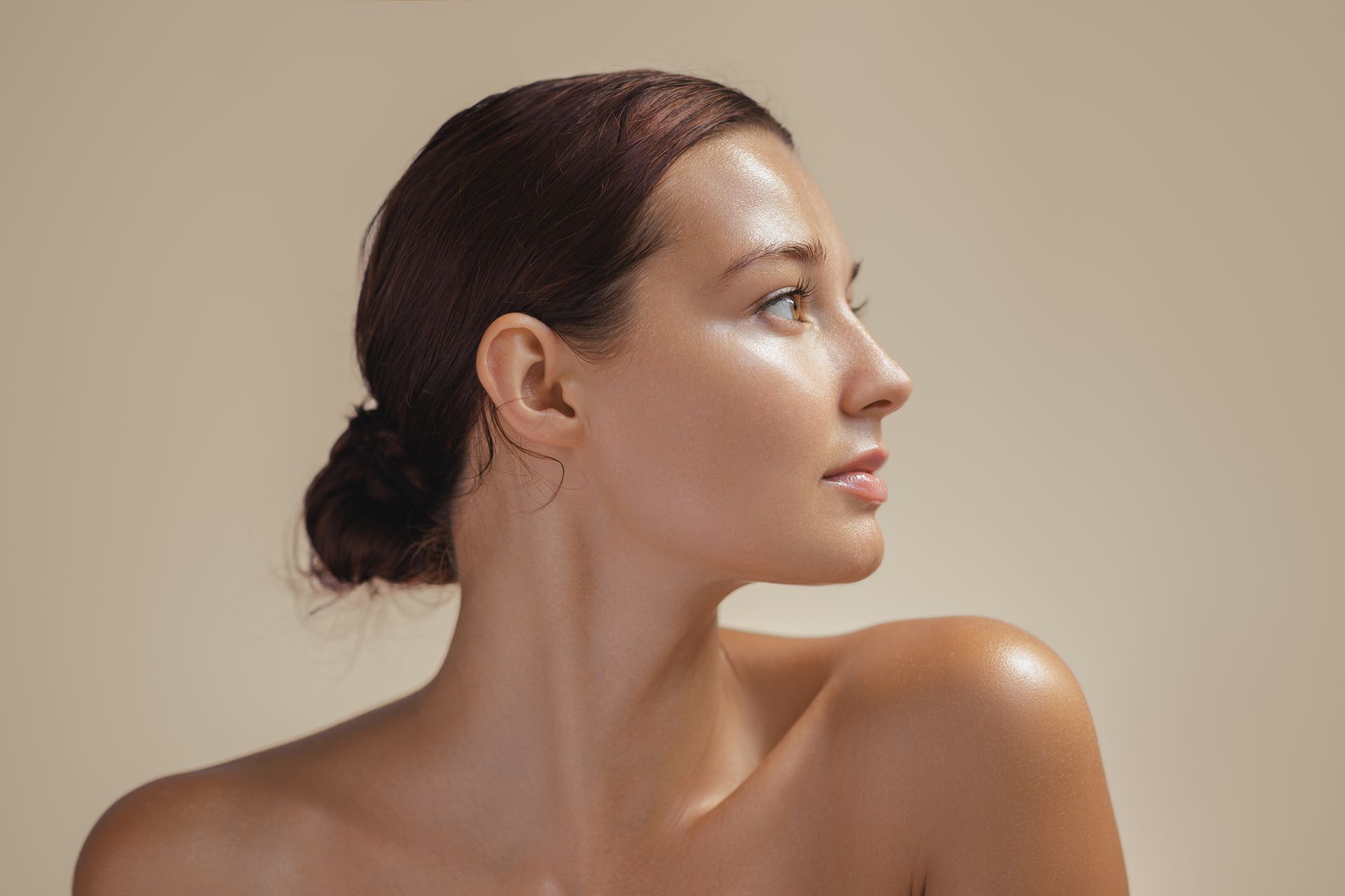 A close up of a woman 's face with her hair in a bun.