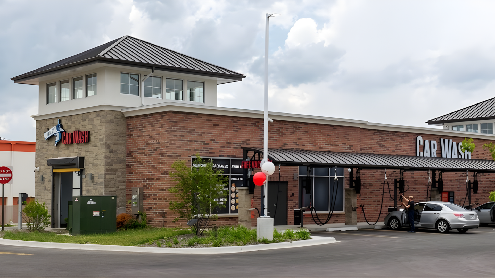 Brick restaurant building with a tower, parked car, and red-and-white balloons by the entrance