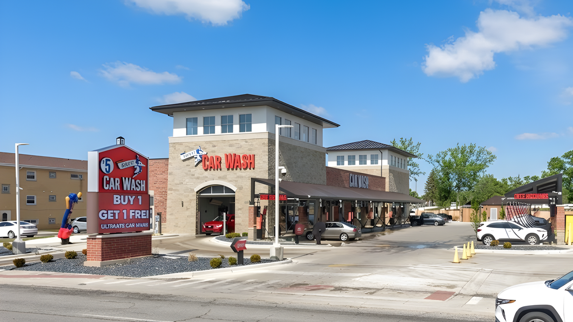 Urban strip mall with a café and shops on a sunny day, featuring a red sign and parked cars.