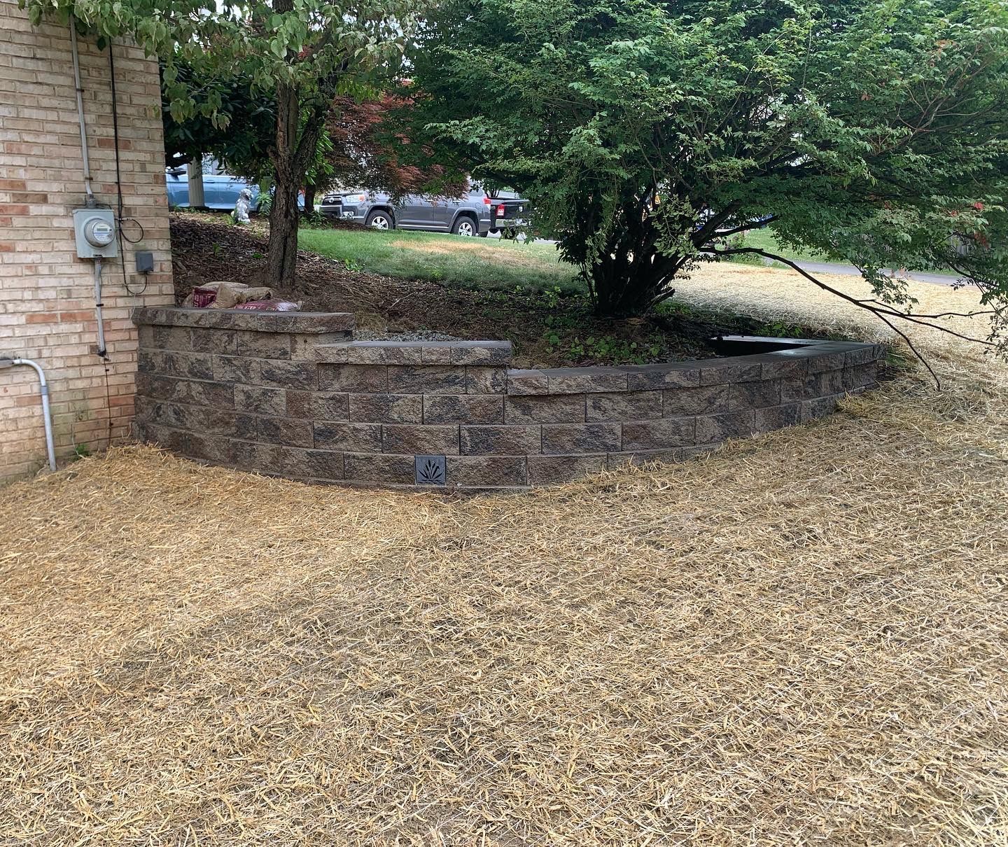 A brick wall is surrounded by gravel in front of a house.