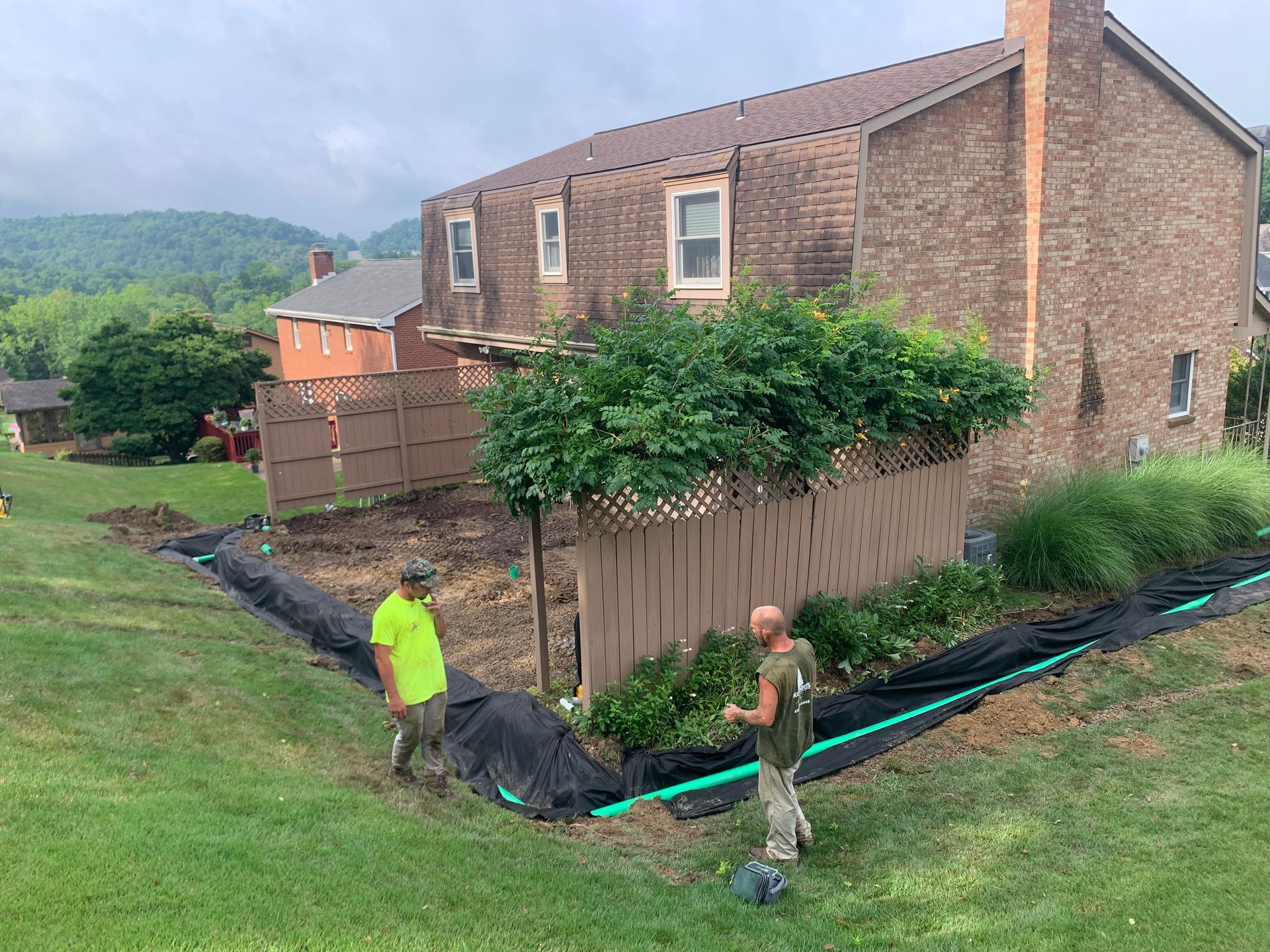 Two men are standing in front of a large brick house.