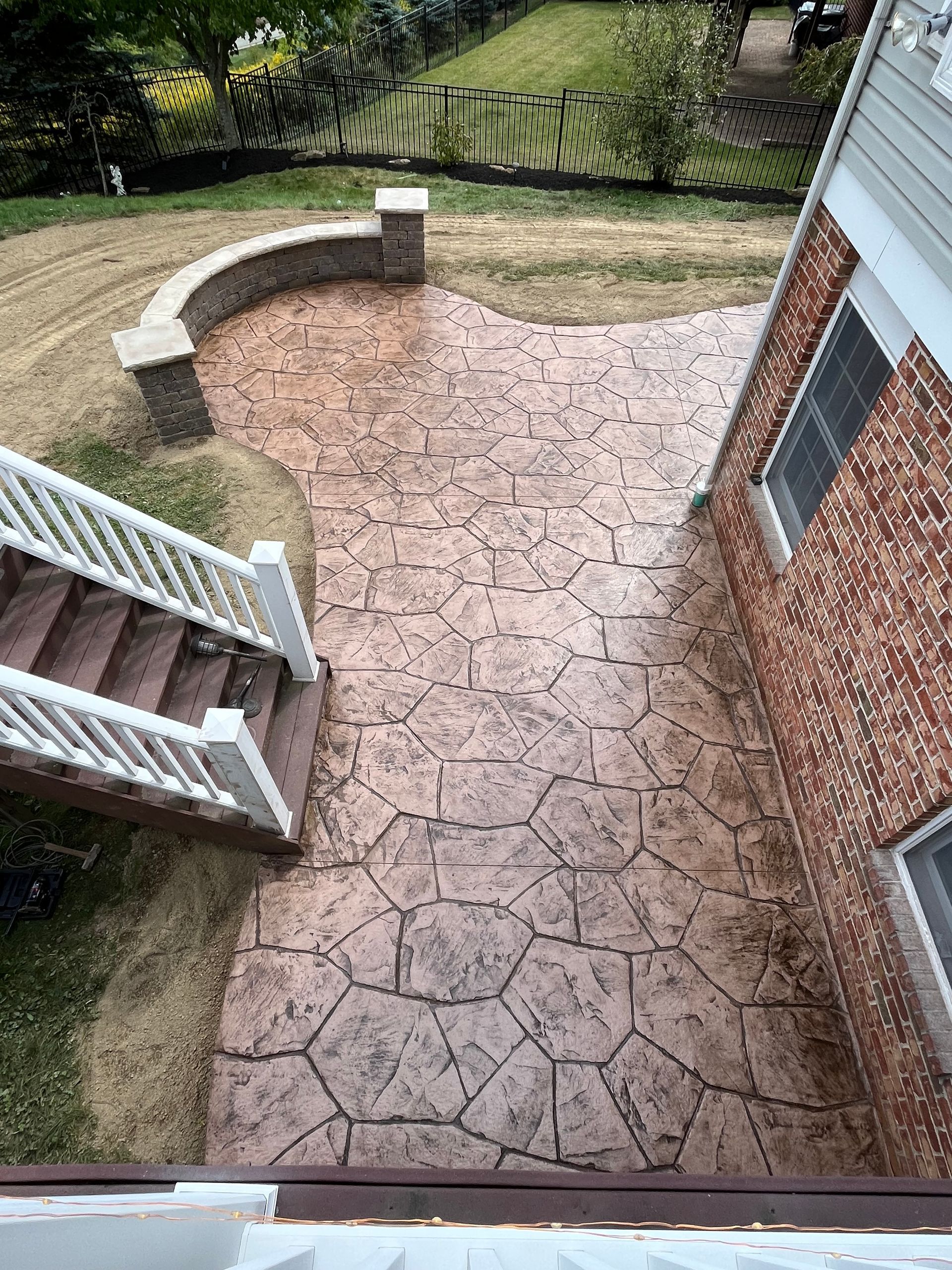 A brick wall surrounded by mulch and a wooden fence.