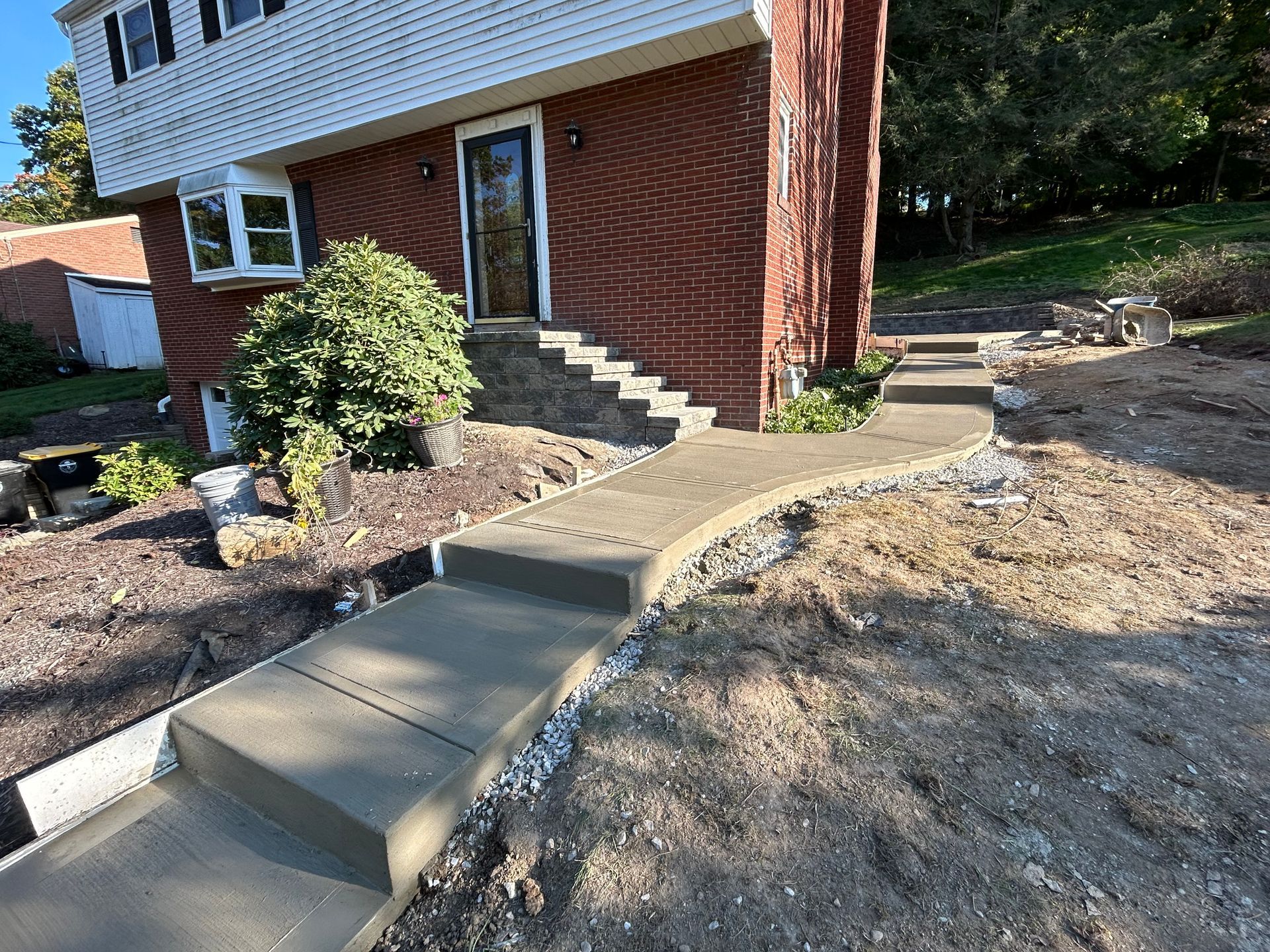 A concrete walkway is being built in front of a brick house.