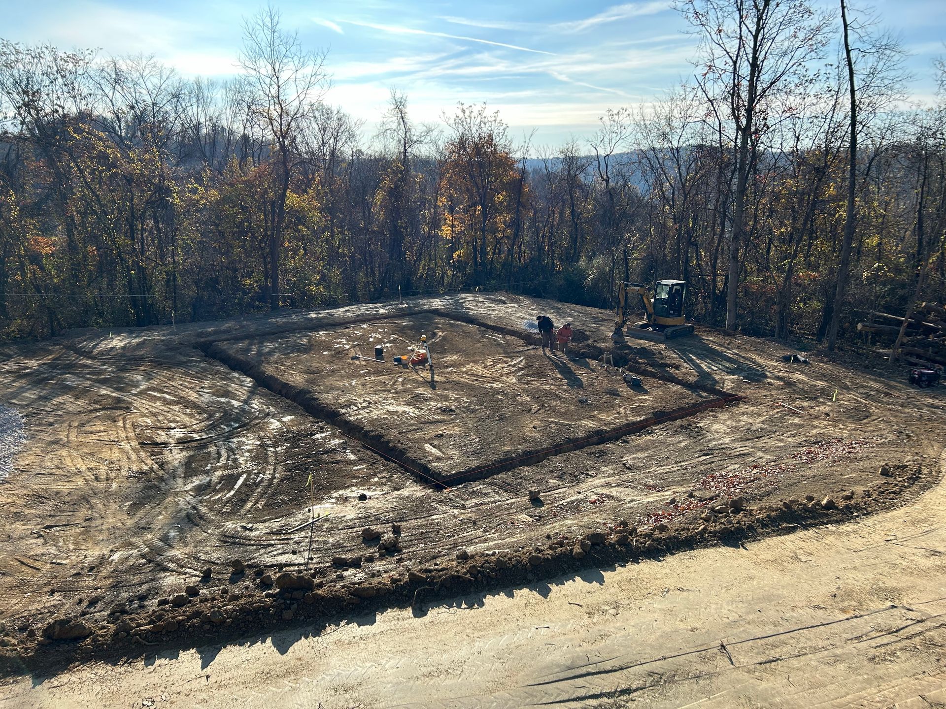 An aerial view of a dirt field with trees in the background.
