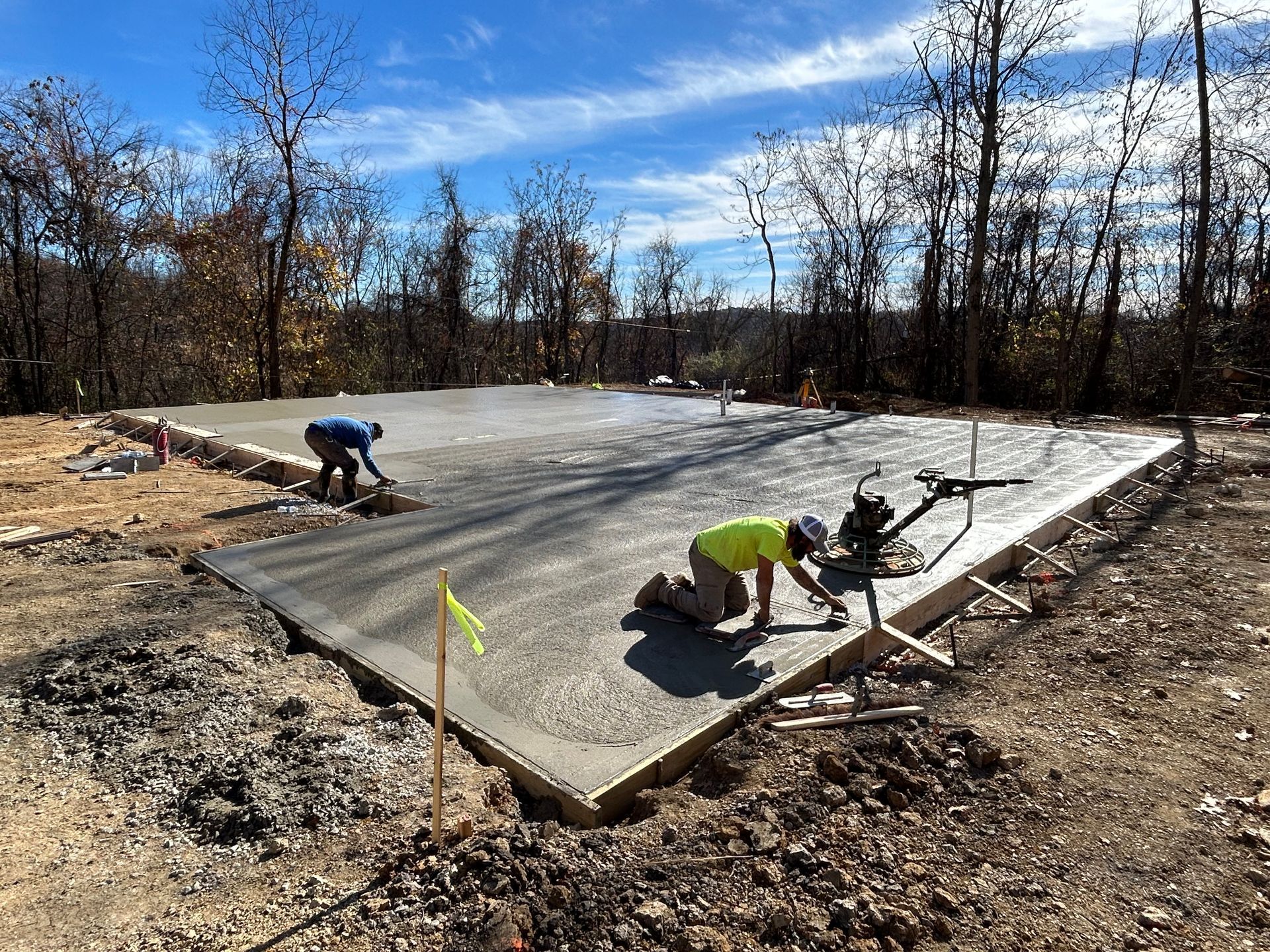 A couple of men are working on a concrete floor.