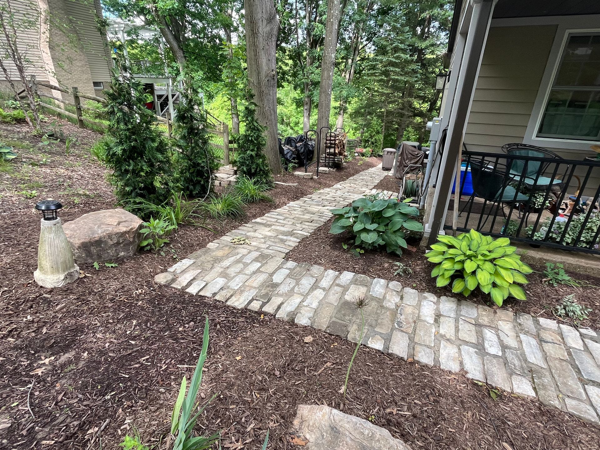 A brick walkway leading to a house in the woods.