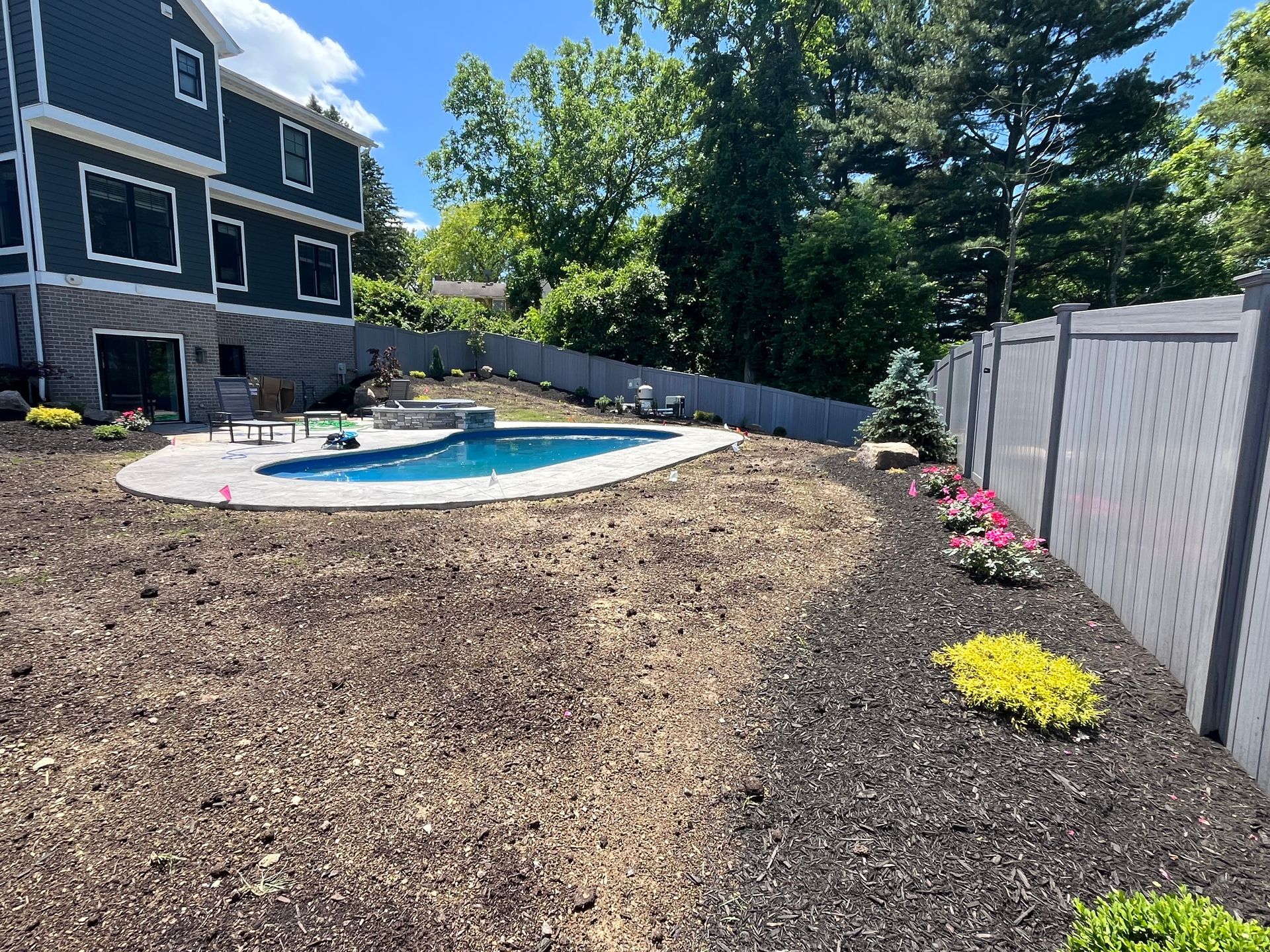 There is a large swimming pool in the backyard of a house.