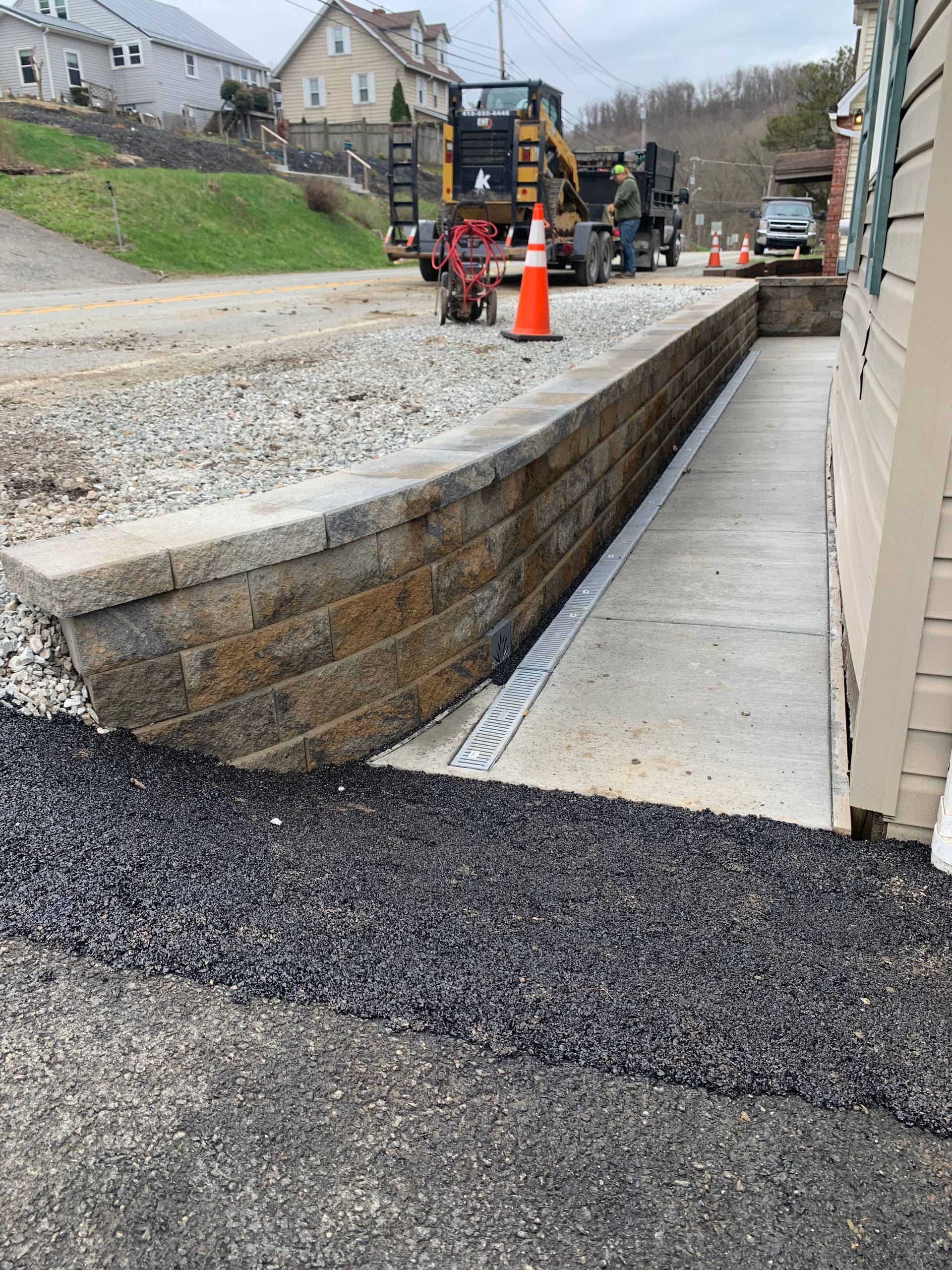 A construction site with a brick wall and a concrete walkway.