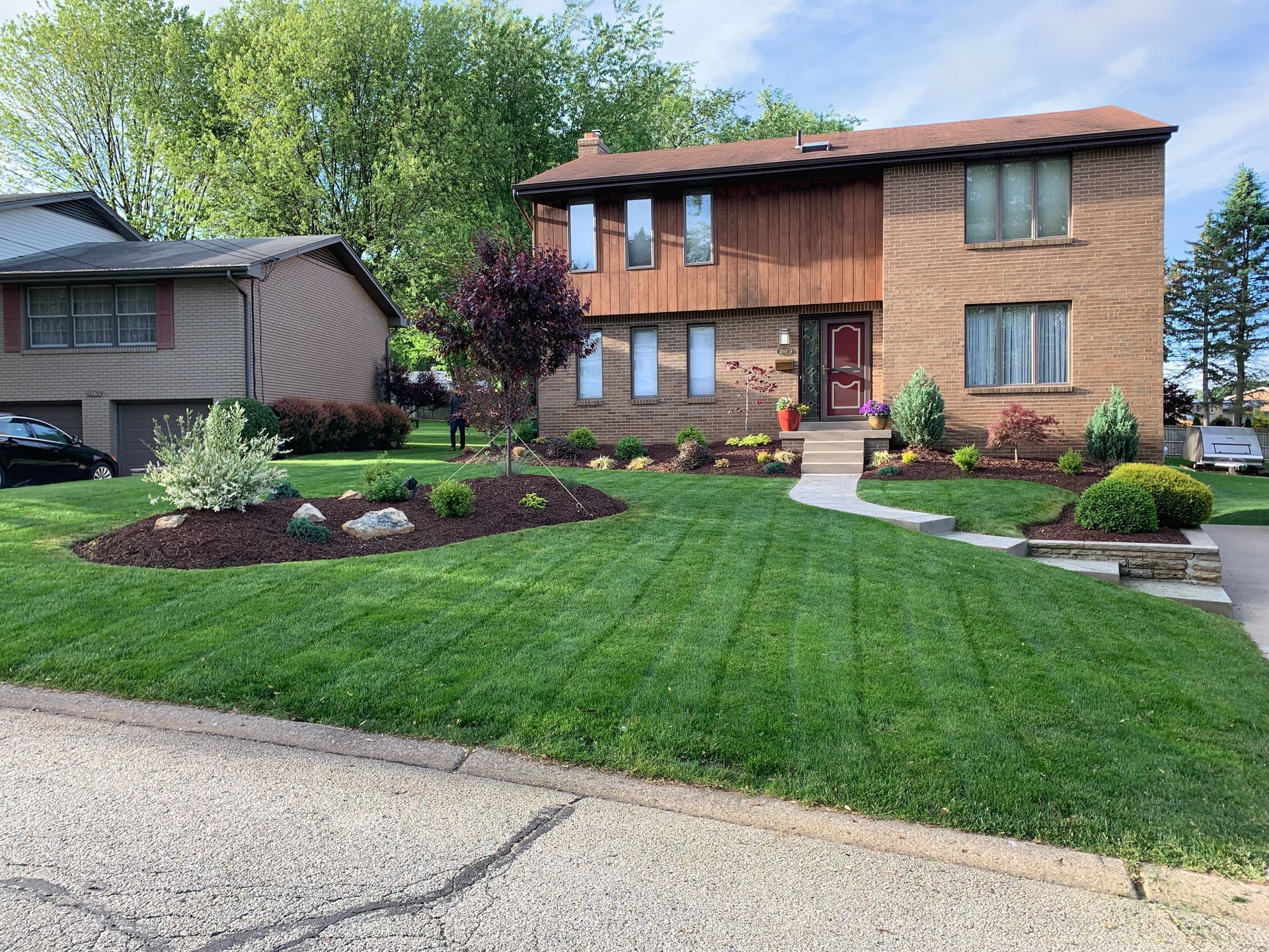 A brick house with a lush green lawn in front of it.