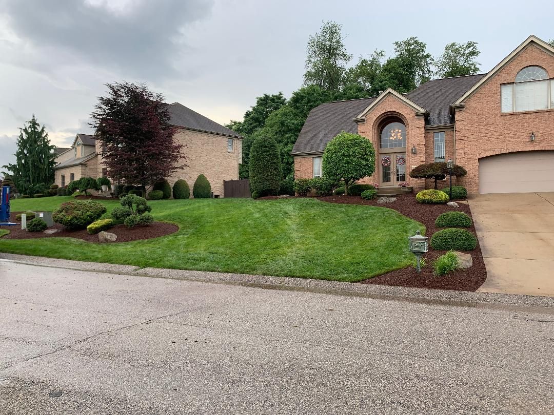 A large brick house with a large lawn in front of it.
