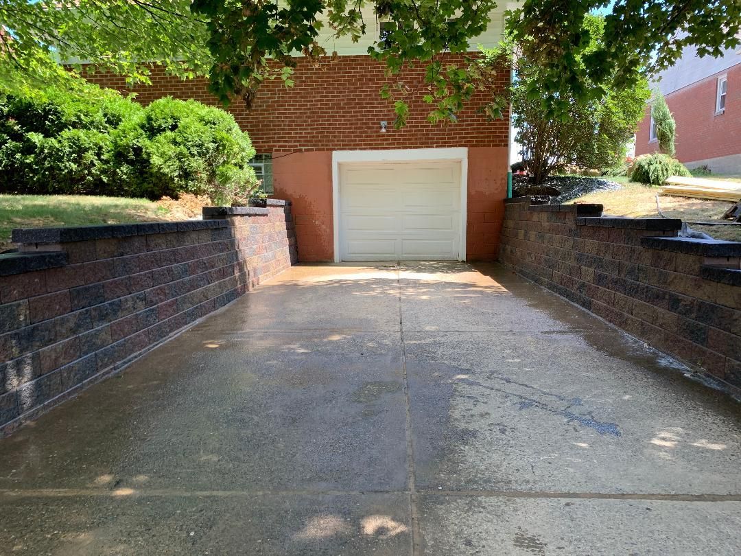 A driveway leading to a garage with a brick wall.