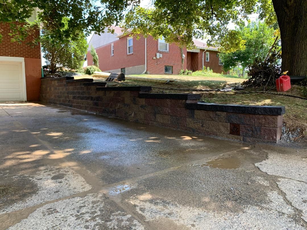 A driveway with a brick wall and a garage in the background.
