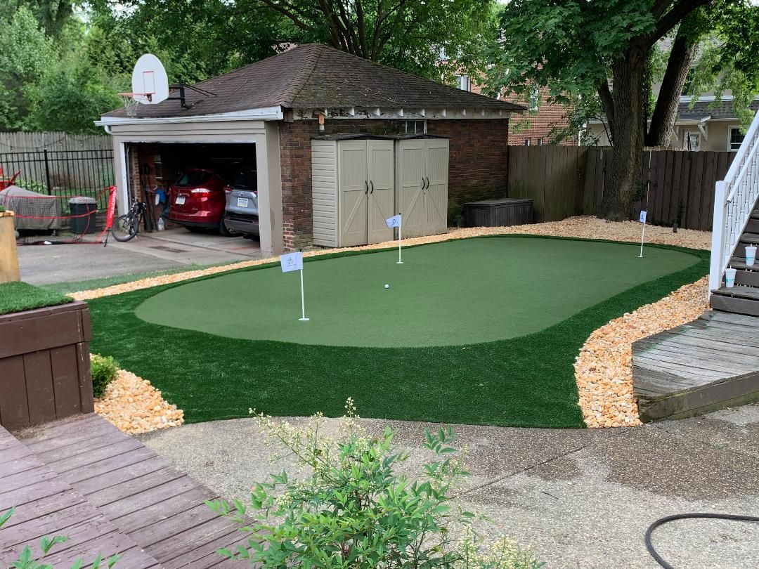 A backyard with a putting green and a garage.
