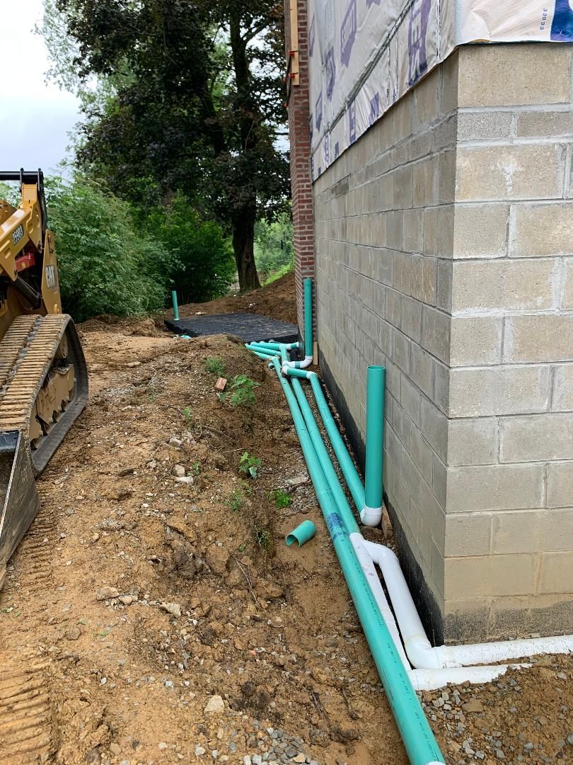 A bulldozer is driving down a dirt road next to a brick building.