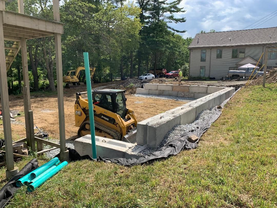 A construction site with a bulldozer and a house in the background.