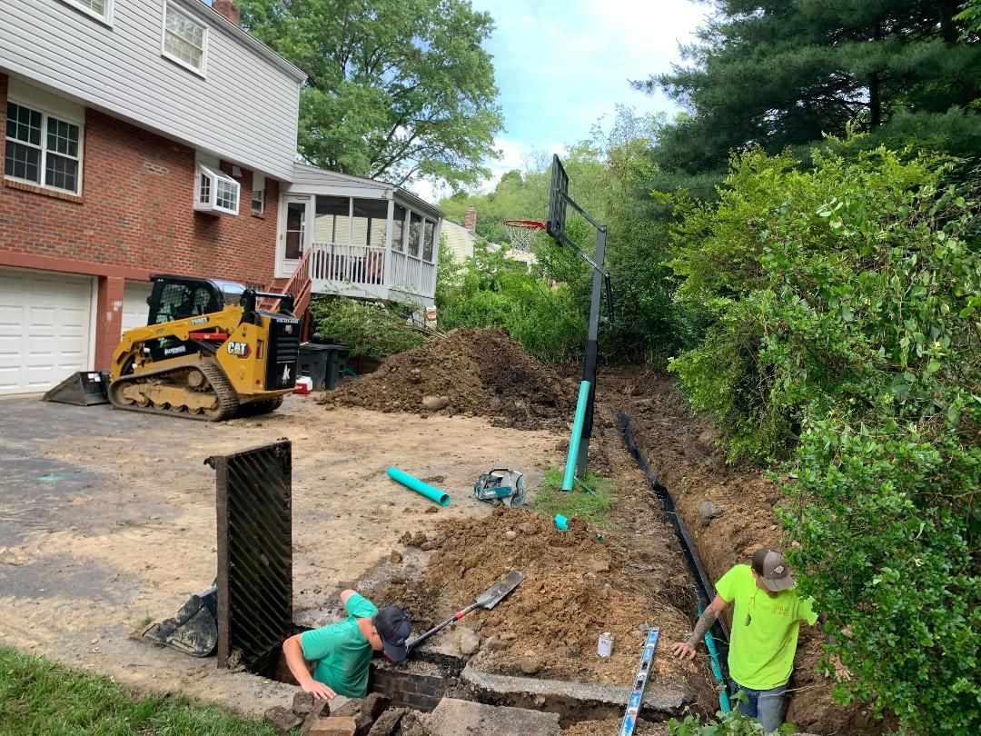 A couple of men are working in the dirt in front of a house.