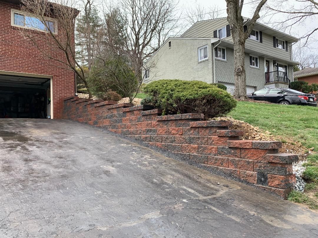 A driveway leading to a house with a brick wall and stairs.