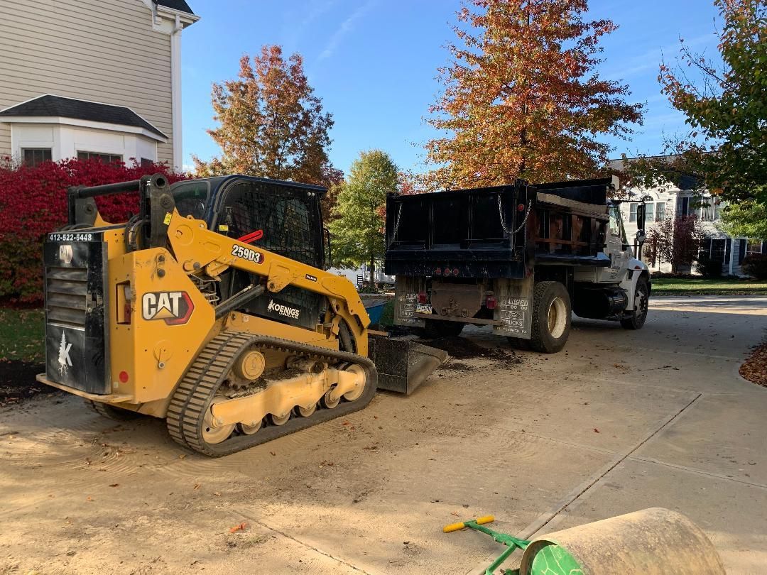 A bulldozer is parked next to a dump truck in a driveway.