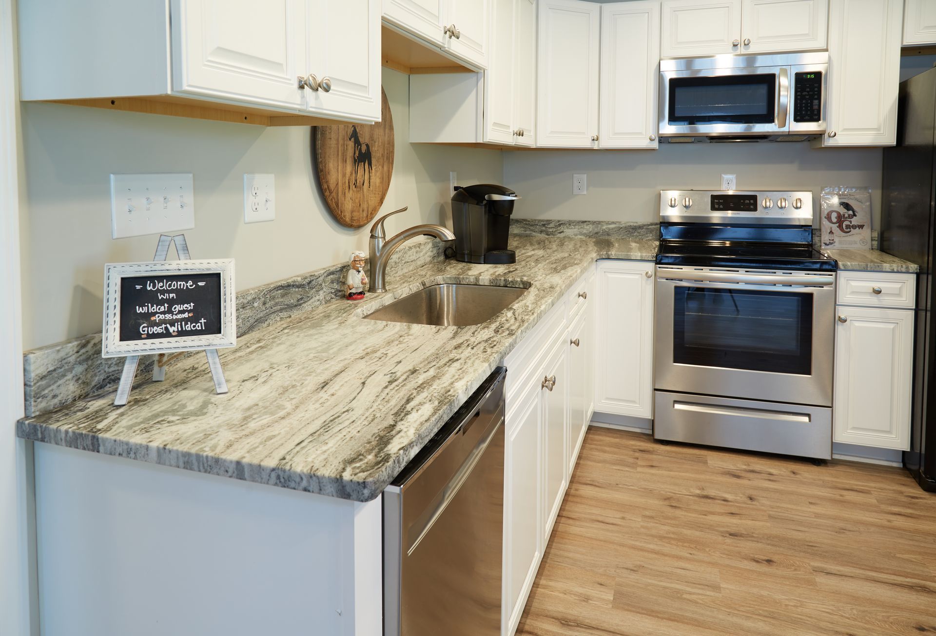 A kitchen with granite counter tops , stainless steel appliances , and white cabinets.