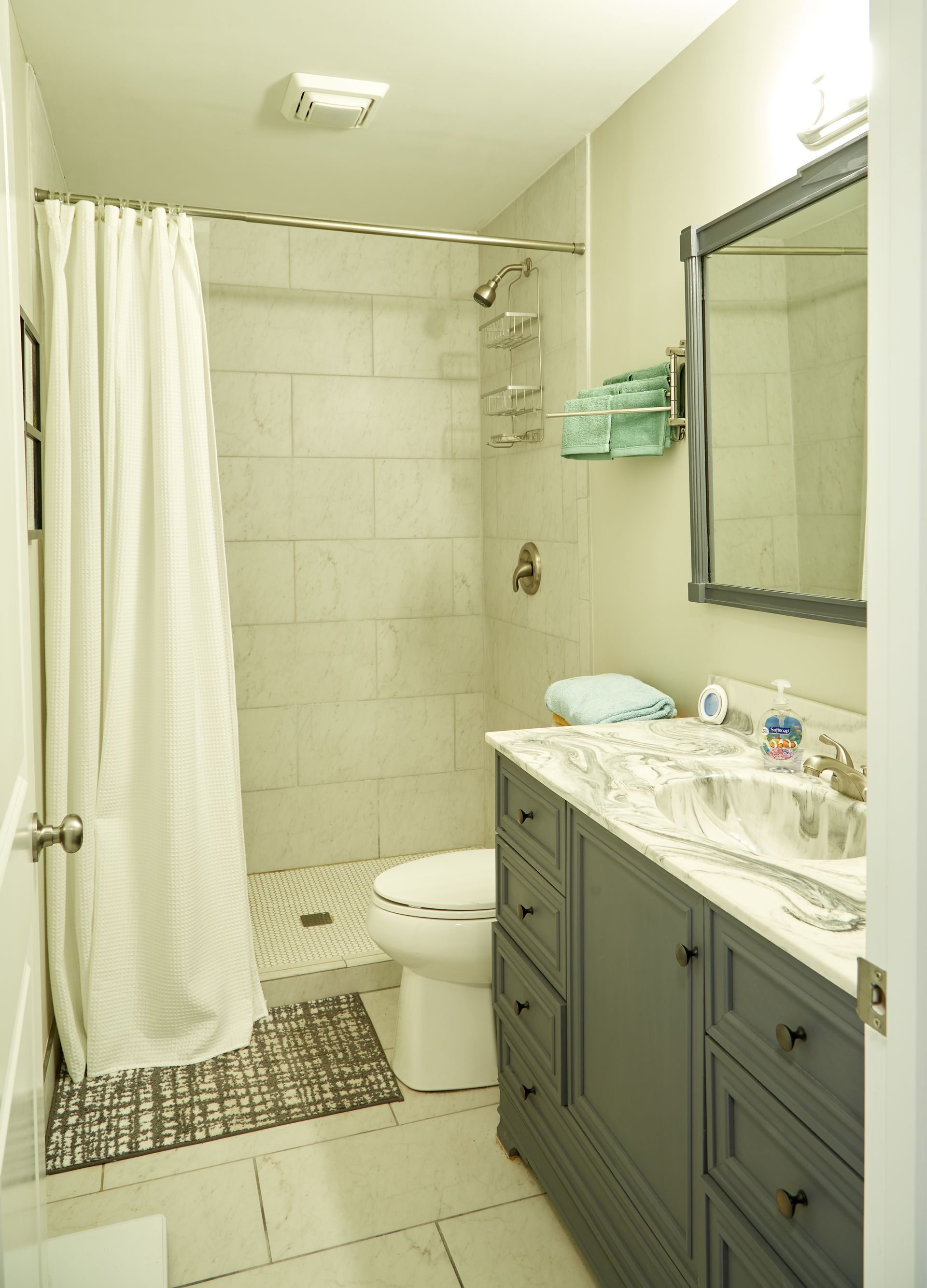A bathroom with a toilet , sink , mirror and shower.
