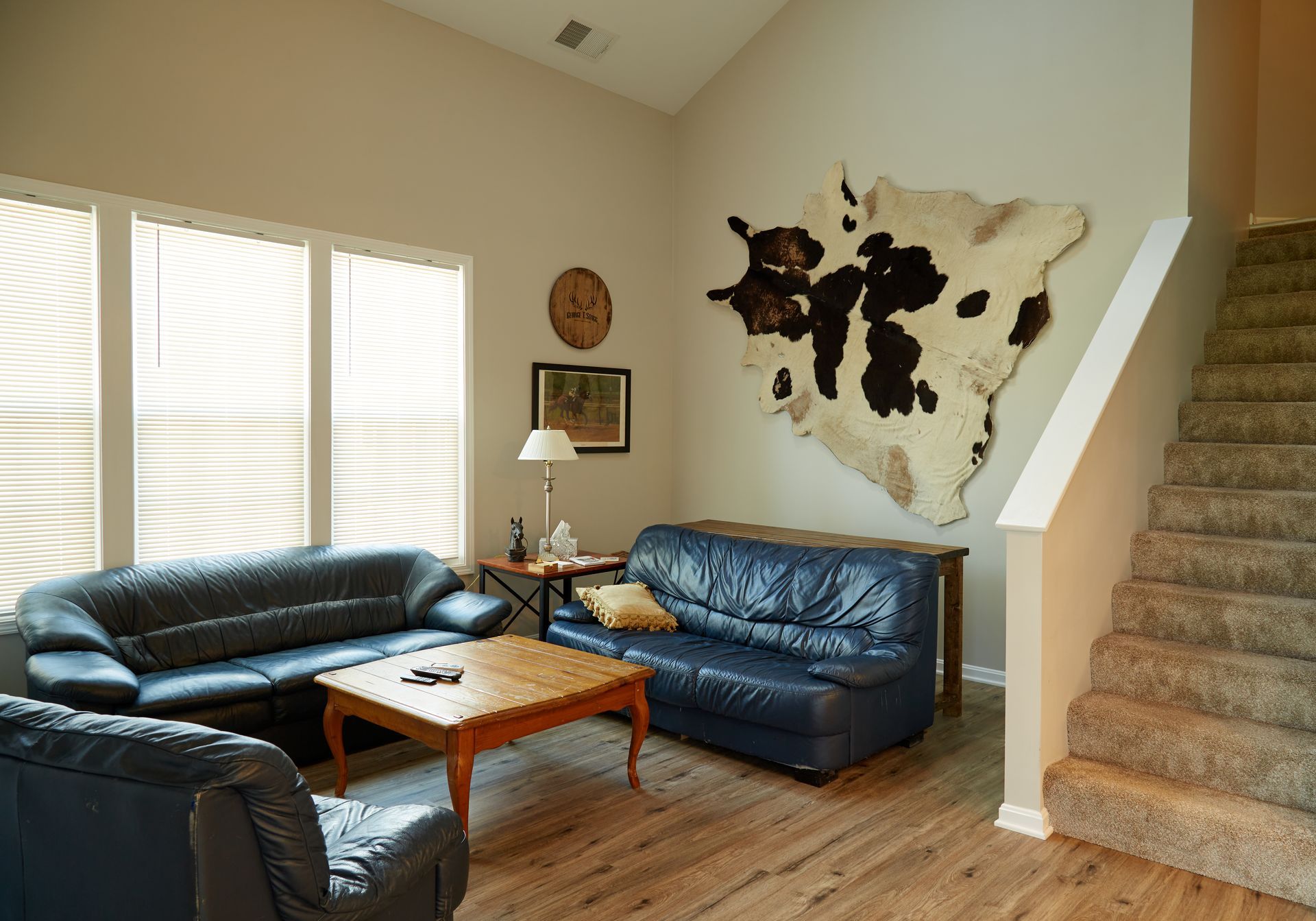 A living room with a couch , chair , coffee table and stairs.