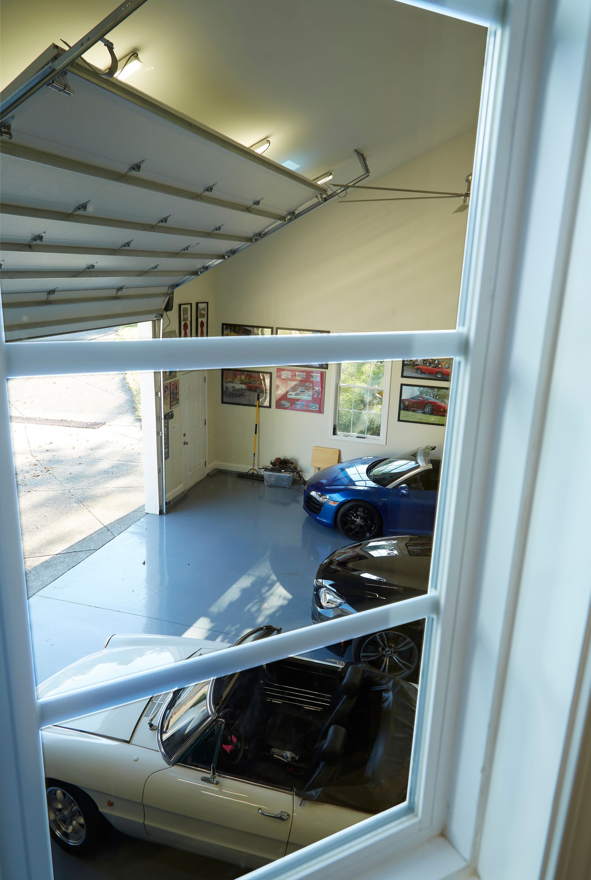 A garage with cars parked in it and a garage door open.