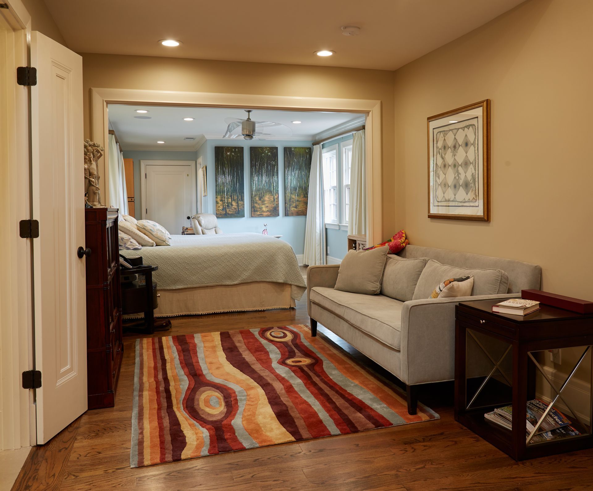 A living room with a couch and a rug leading to a bedroom
