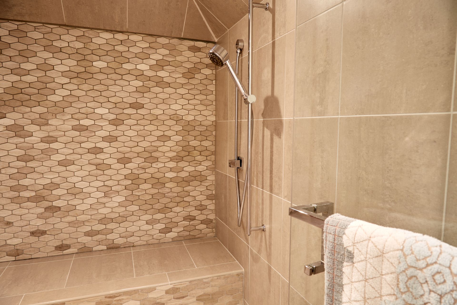 A bathroom with a walk in shower and a bench.