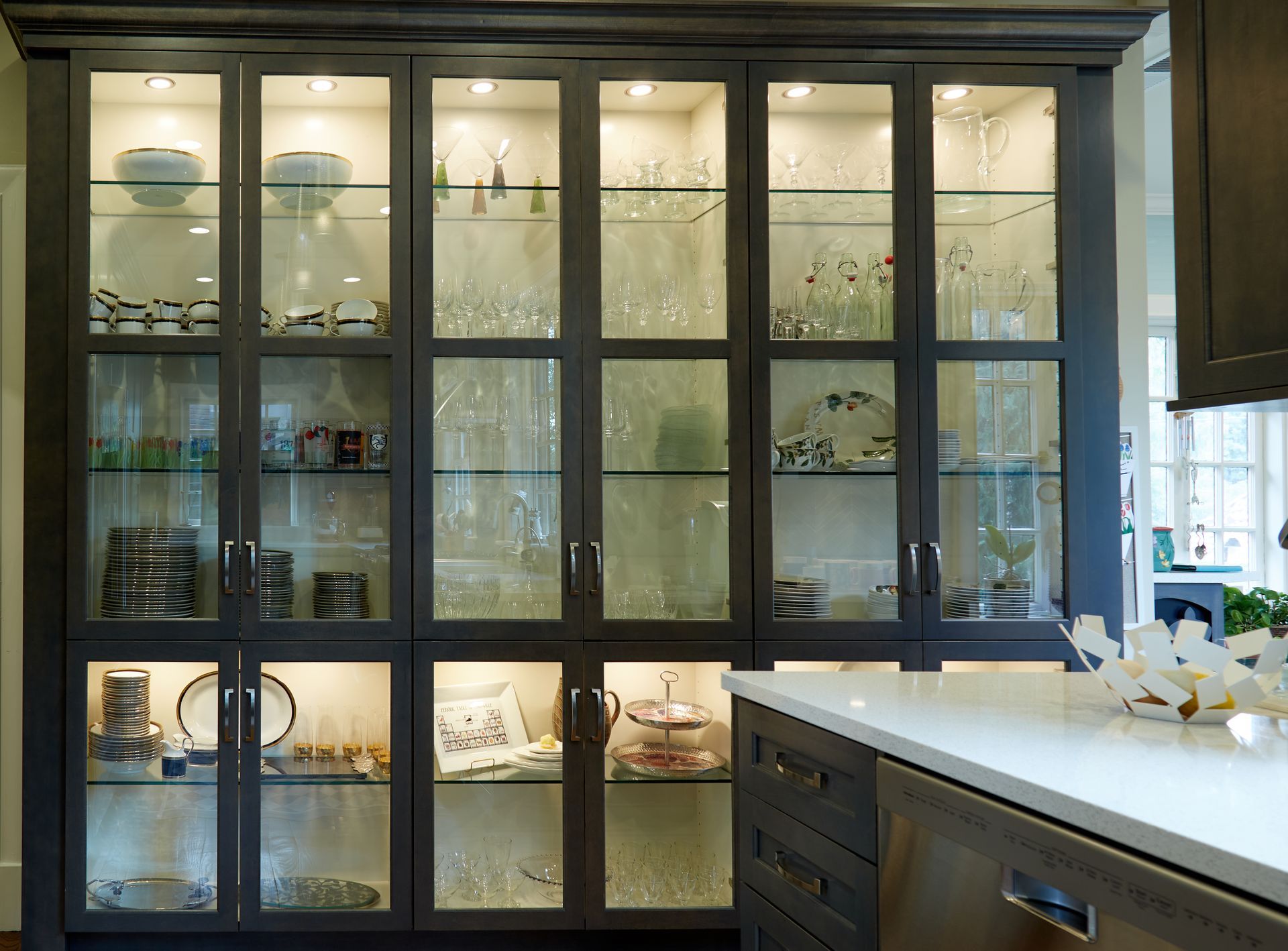 A kitchen with a glass cabinet filled with plates and glasses