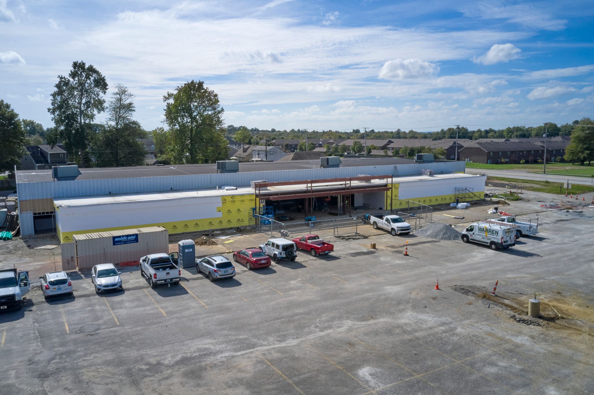 An aerial view of a building under construction with cars parked in front of it.