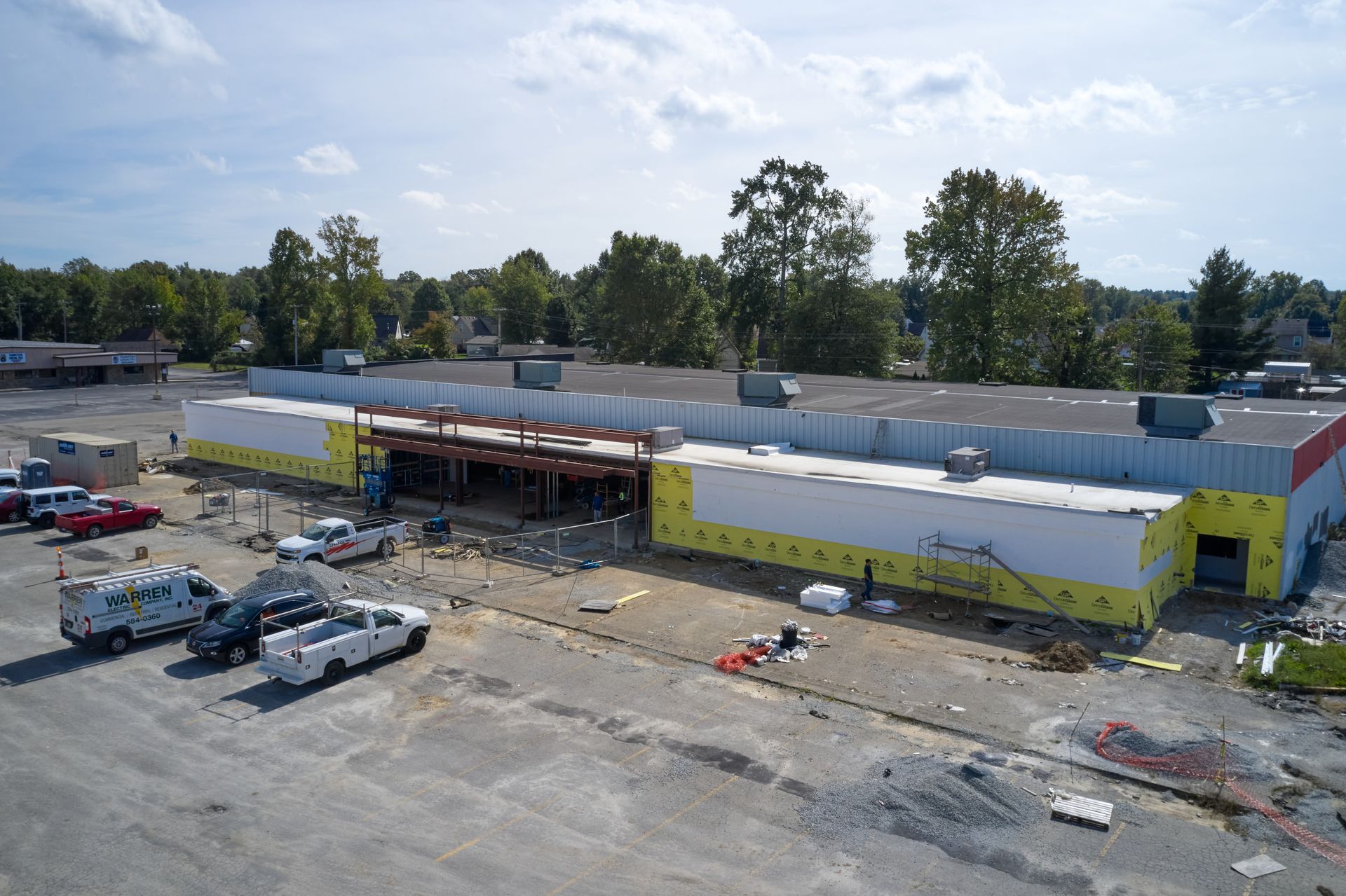 An aerial view of a building under construction with trucks parked in front of it.