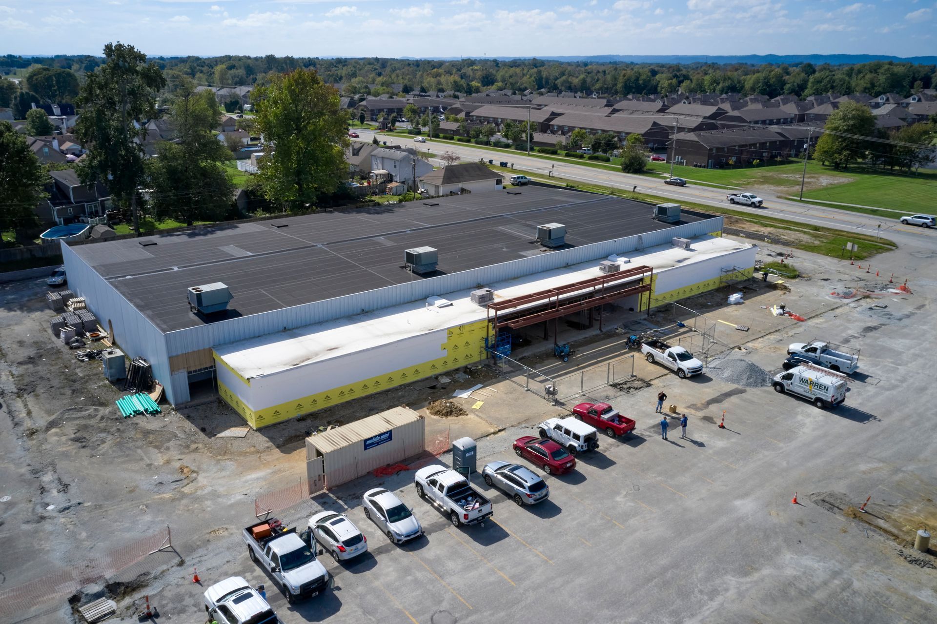 An aerial view of a building under construction with cars parked in front of it.
