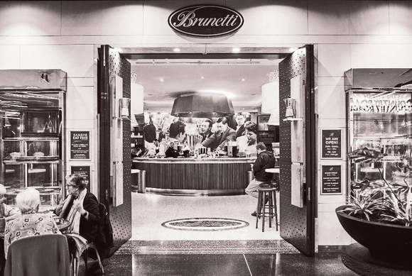Brunetti cafe entrance with open doors, customers, and counter visible inside.