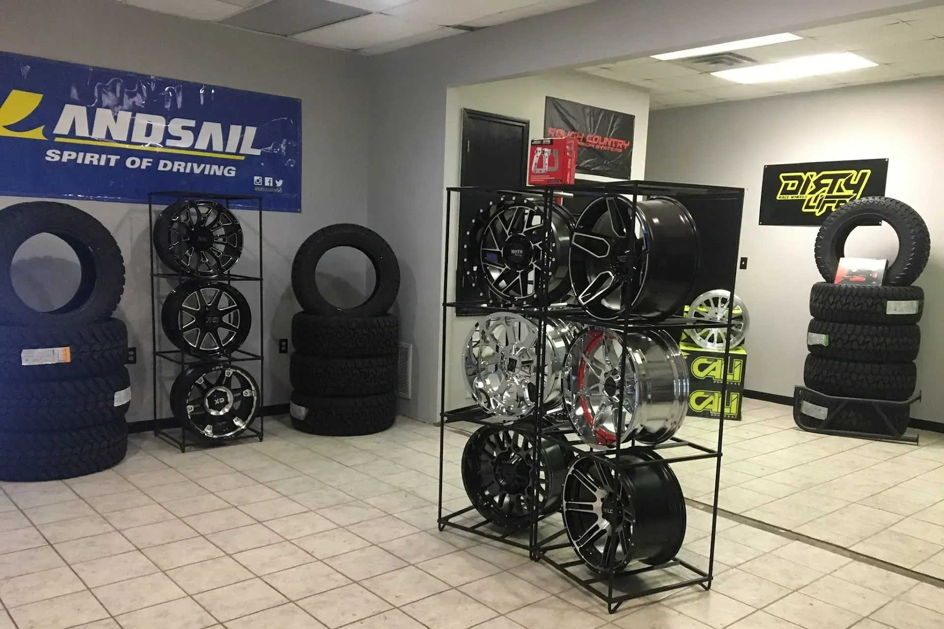 Tire shop interior with displays of tires and rims; banner for 