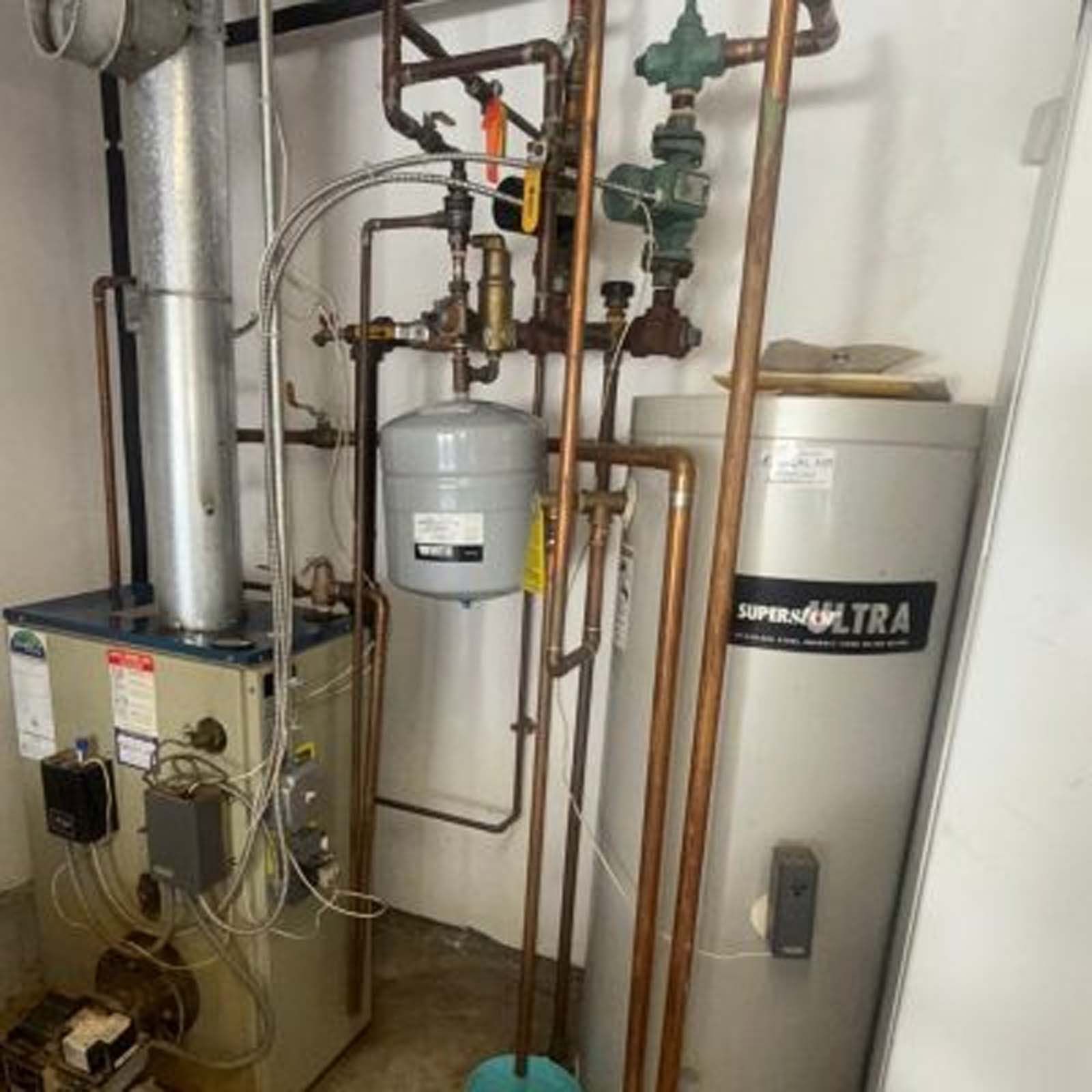 A boiler and a water heater are in a room.