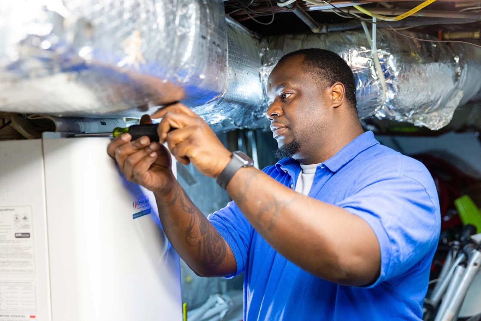 A man in a blue shirt is working on an air conditioner.