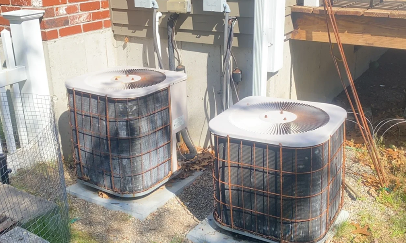 Two air conditioners are sitting outside of a brick building.