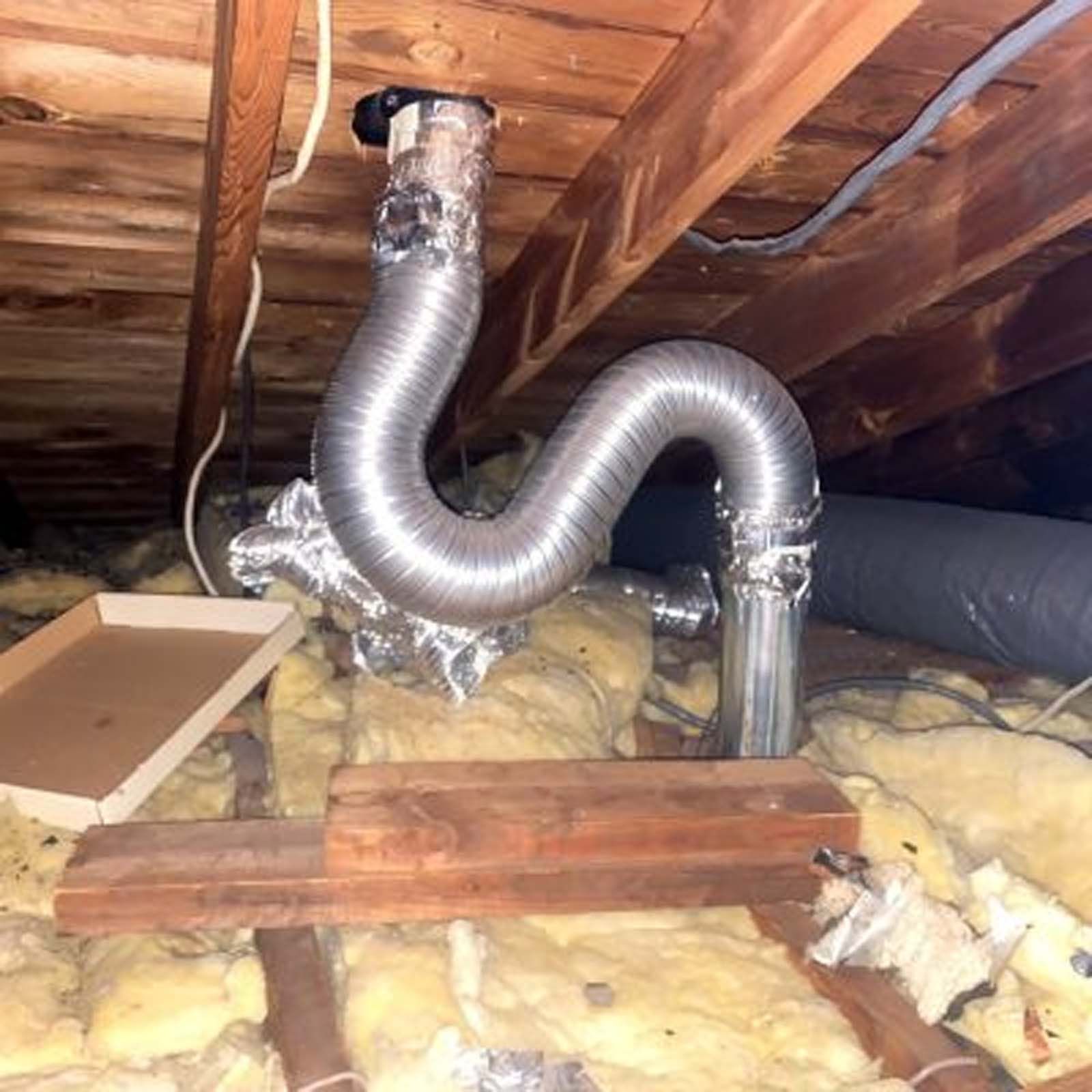 A metal pipe is hanging from the ceiling of an attic